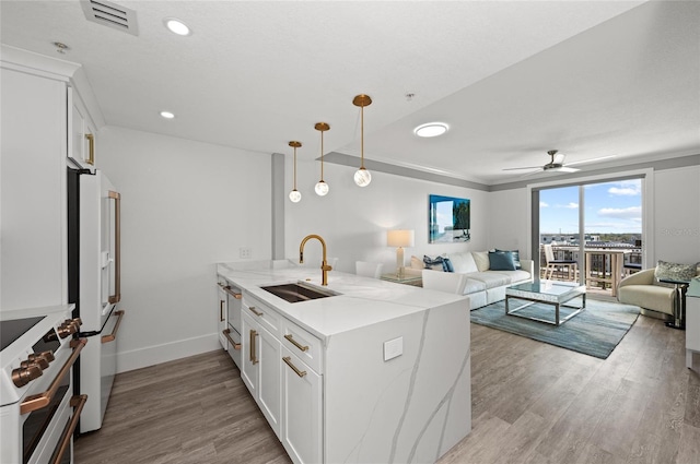 kitchen with stove, open floor plan, a sink, white fridge with ice dispenser, and a peninsula