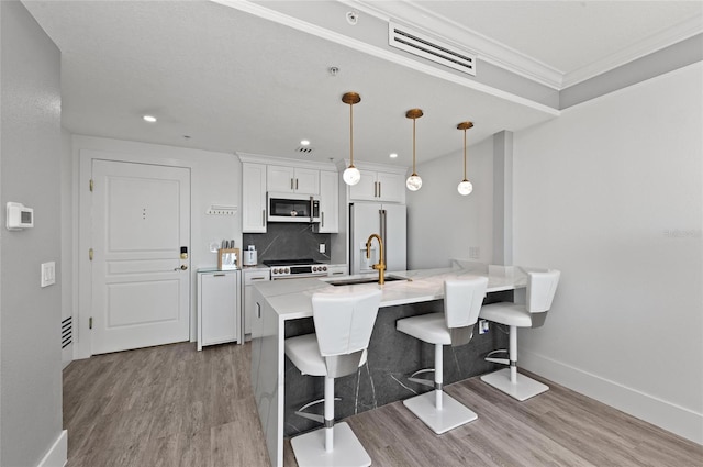 kitchen featuring a kitchen breakfast bar, high end white fridge, a sink, white cabinetry, and backsplash