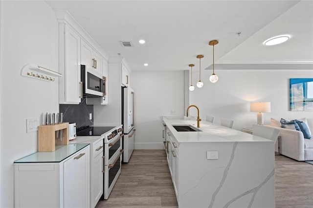 kitchen featuring white appliances, a sink, light wood-style floors, open floor plan, and white cabinets