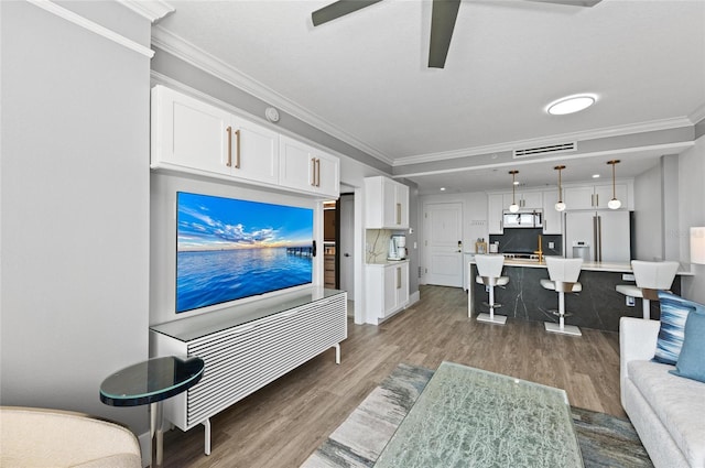 living area with a ceiling fan, visible vents, crown molding, and wood finished floors