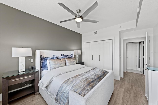 bedroom with light wood-style floors, a closet, visible vents, and a ceiling fan