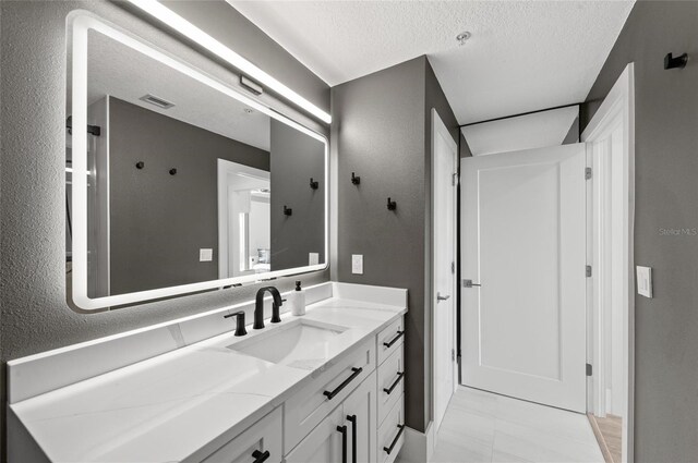 bathroom with a textured ceiling, a textured wall, vanity, and visible vents