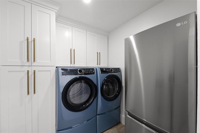 clothes washing area featuring cabinet space and washer and clothes dryer