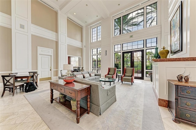 living room with french doors, beamed ceiling, a decorative wall, and a towering ceiling