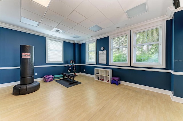 exercise area featuring crown molding, baseboards, and wood finished floors