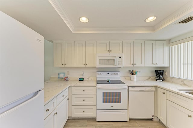 kitchen with ornamental molding, white appliances, a raised ceiling, and white cabinetry