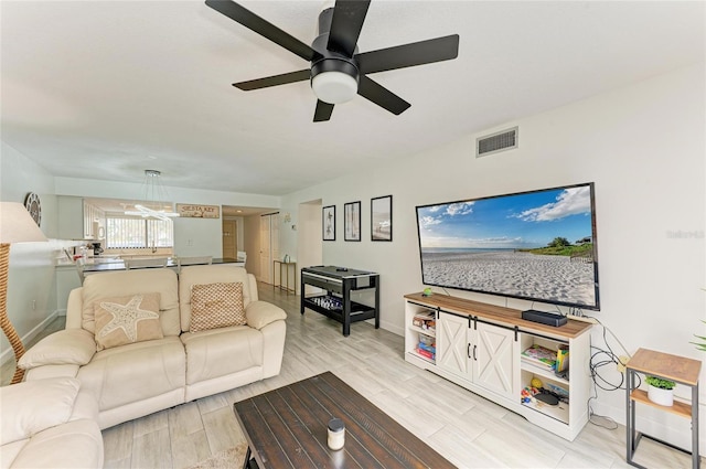 living area featuring ceiling fan, visible vents, baseboards, and wood finish floors