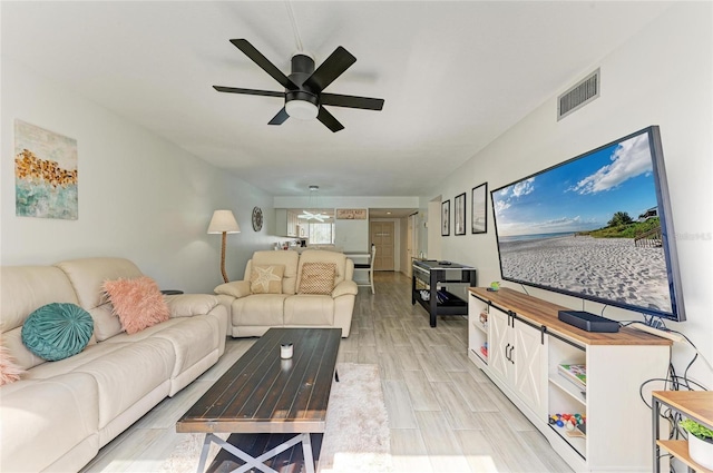 living area featuring wood tiled floor, visible vents, and ceiling fan