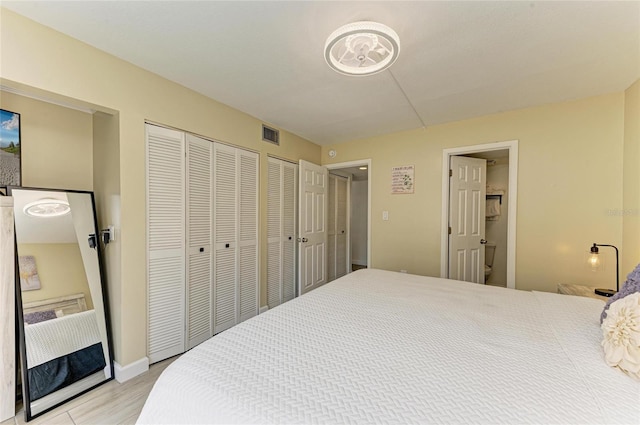 bedroom featuring light wood-type flooring, visible vents, and multiple closets