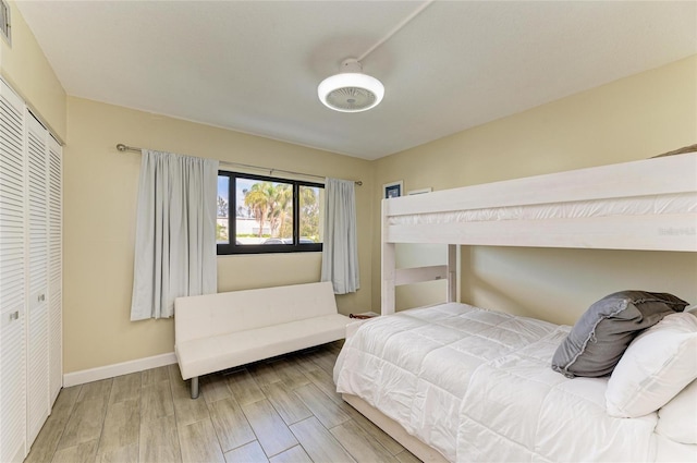 bedroom with a closet, wood finished floors, visible vents, and baseboards