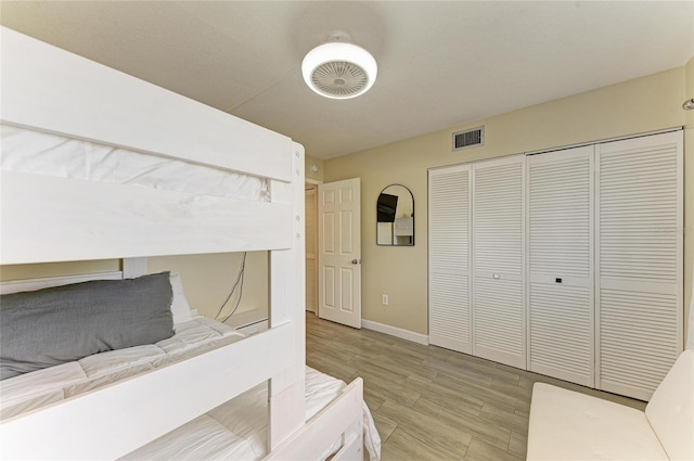 bedroom featuring light wood-type flooring, a closet, visible vents, and baseboards