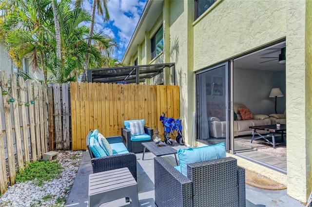 view of patio featuring outdoor lounge area, fence, and ceiling fan