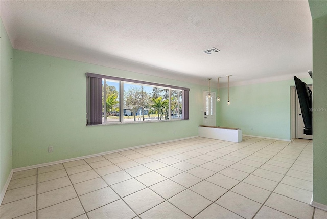 spare room featuring light tile patterned floors, visible vents, baseboards, and a textured ceiling