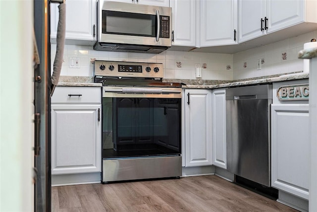 kitchen with white cabinets, wood finished floors, tasteful backsplash, and stainless steel appliances