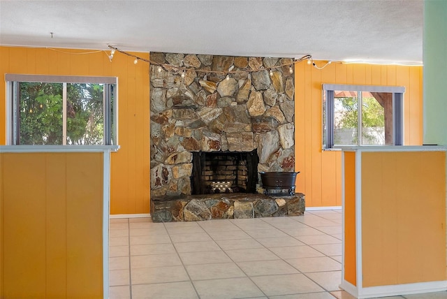 tiled living room featuring a stone fireplace and a textured ceiling