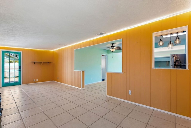 empty room with visible vents, a ceiling fan, crown molding, and a textured ceiling