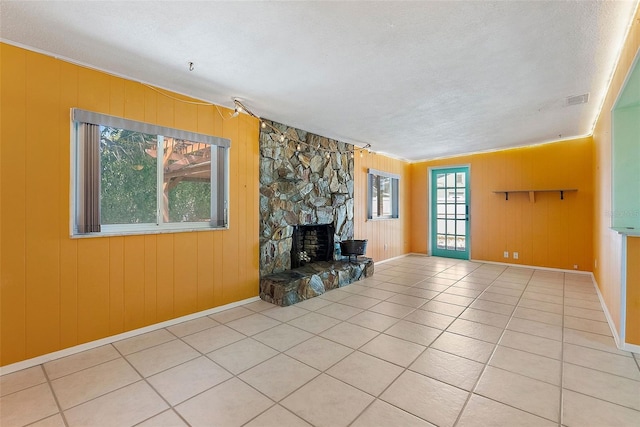 unfurnished living room featuring visible vents, a textured ceiling, a fireplace, tile patterned flooring, and baseboards