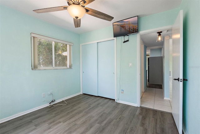 unfurnished bedroom featuring ceiling fan, a closet, baseboards, and wood finished floors