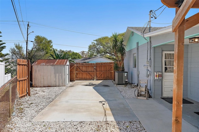 view of patio with an outbuilding, a gate, fence, a shed, and central AC