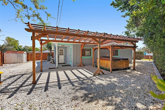 back of property featuring a hot tub, a fenced backyard, an outdoor structure, a storage unit, and a patio