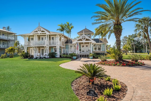 view of front of house with a front yard, a balcony, and french doors