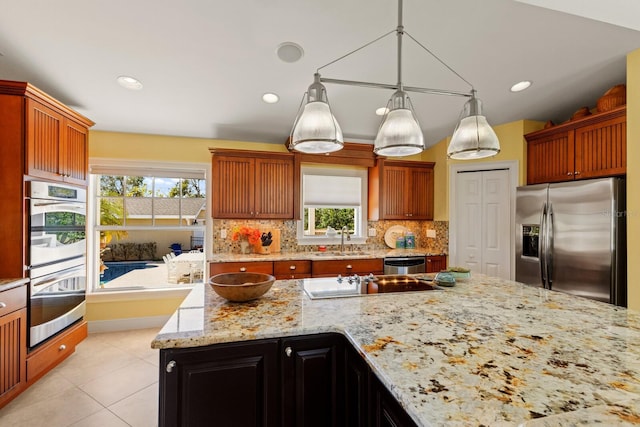 kitchen with a sink, decorative light fixtures, backsplash, appliances with stainless steel finishes, and lofted ceiling