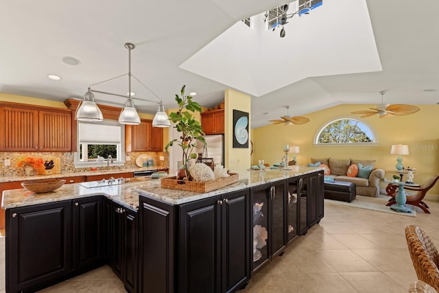 kitchen featuring dark cabinetry, a large island, a wealth of natural light, and vaulted ceiling