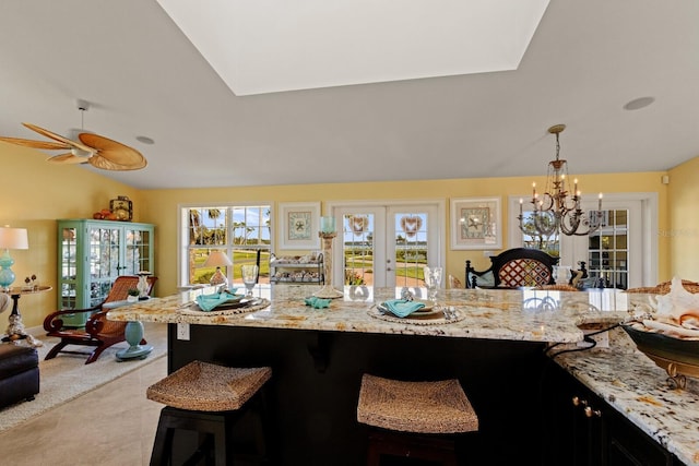 kitchen with light stone countertops, a breakfast bar area, vaulted ceiling, french doors, and hanging light fixtures