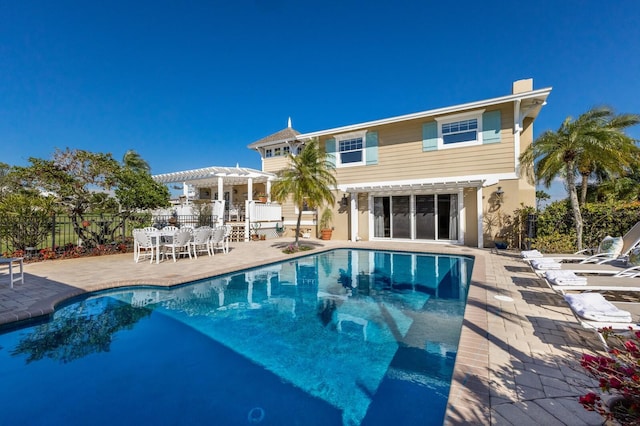 rear view of house with a fenced in pool, a patio, fence, and a pergola