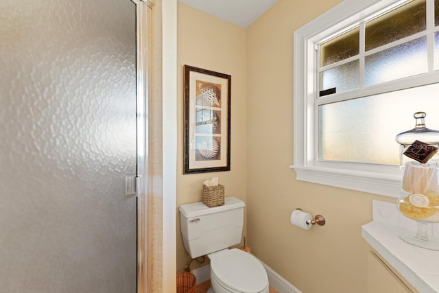 bathroom featuring toilet, baseboards, and a stall shower