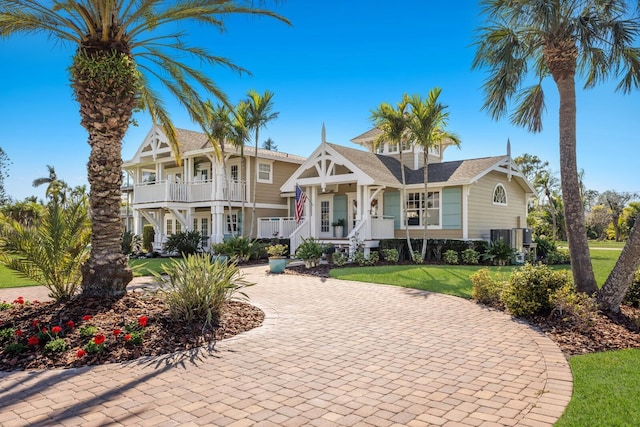 view of front of home with central air condition unit, a front yard, covered porch, decorative driveway, and a balcony