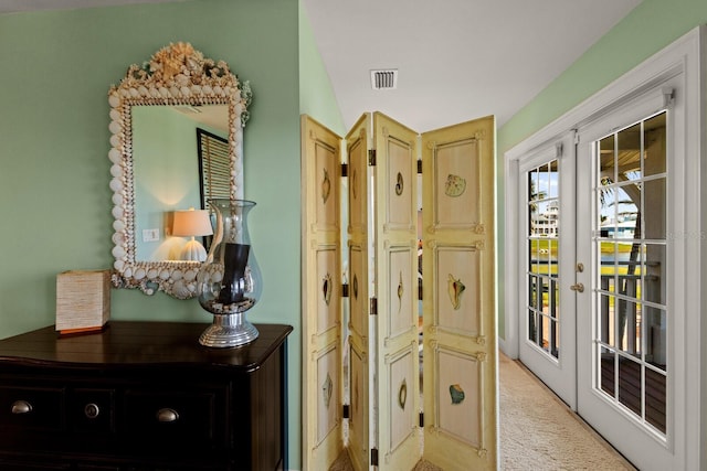 hallway with light carpet, visible vents, and french doors