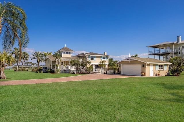 view of front of home with stucco siding, a front lawn, decorative driveway, fence, and a garage