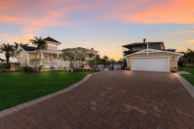 view of front of property featuring a porch, an attached garage, decorative driveway, and a front lawn