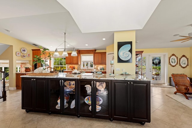 kitchen featuring recessed lighting, light stone countertops, backsplash, and vaulted ceiling