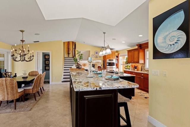 kitchen featuring light stone countertops, a kitchen bar, vaulted ceiling, decorative backsplash, and stainless steel double oven