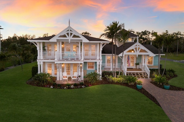 back of house featuring a lawn, decorative driveway, a patio, french doors, and a balcony