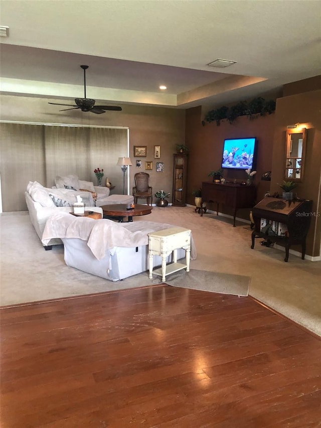 living area featuring visible vents, carpet flooring, a ceiling fan, and wood finished floors