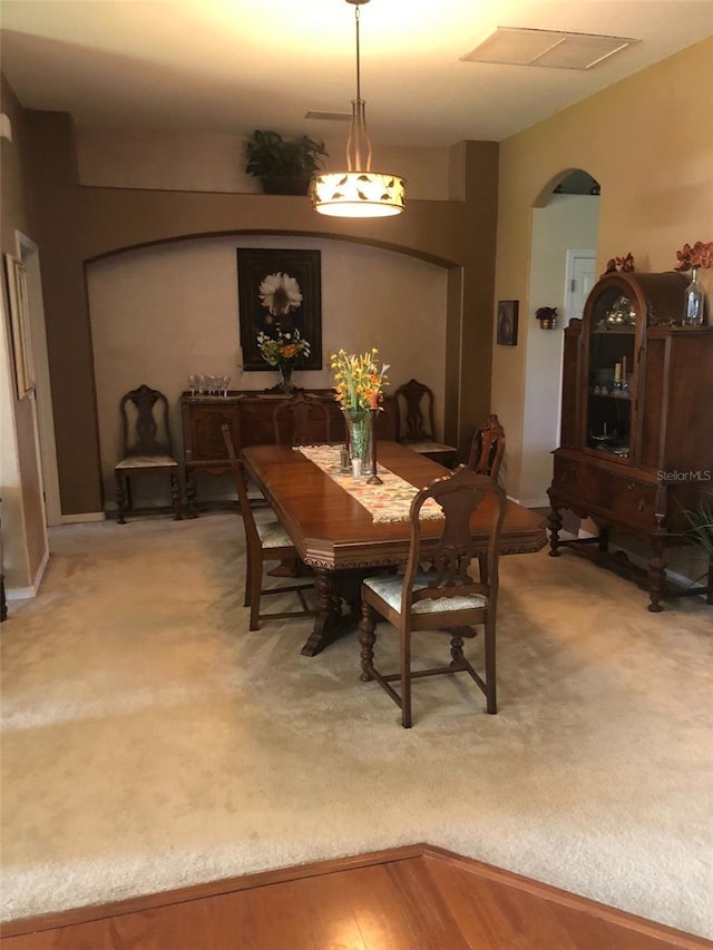 dining space featuring arched walkways and light wood finished floors