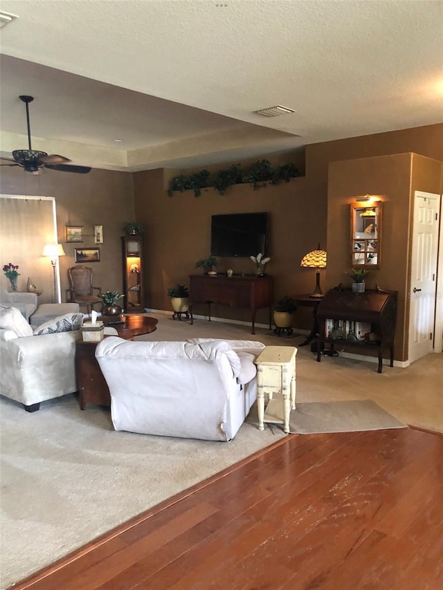 living room featuring a textured ceiling, wood finished floors, visible vents, and ceiling fan