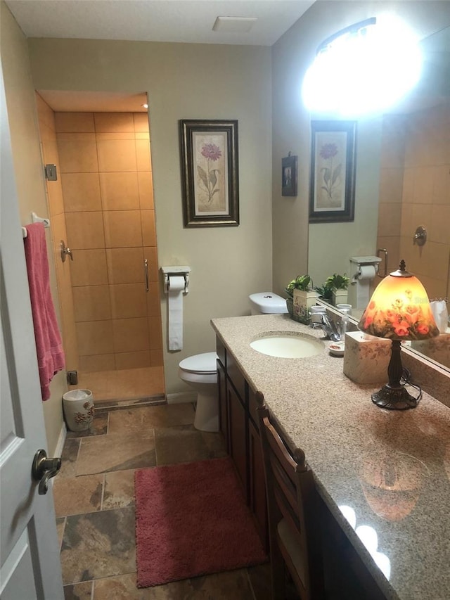 full bathroom with vanity, baseboards, a shower stall, stone finish floor, and toilet