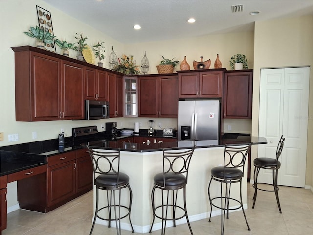 kitchen featuring stainless steel appliances, a breakfast bar, visible vents, and a kitchen island