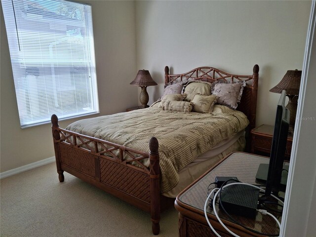 carpeted bedroom featuring multiple windows and baseboards