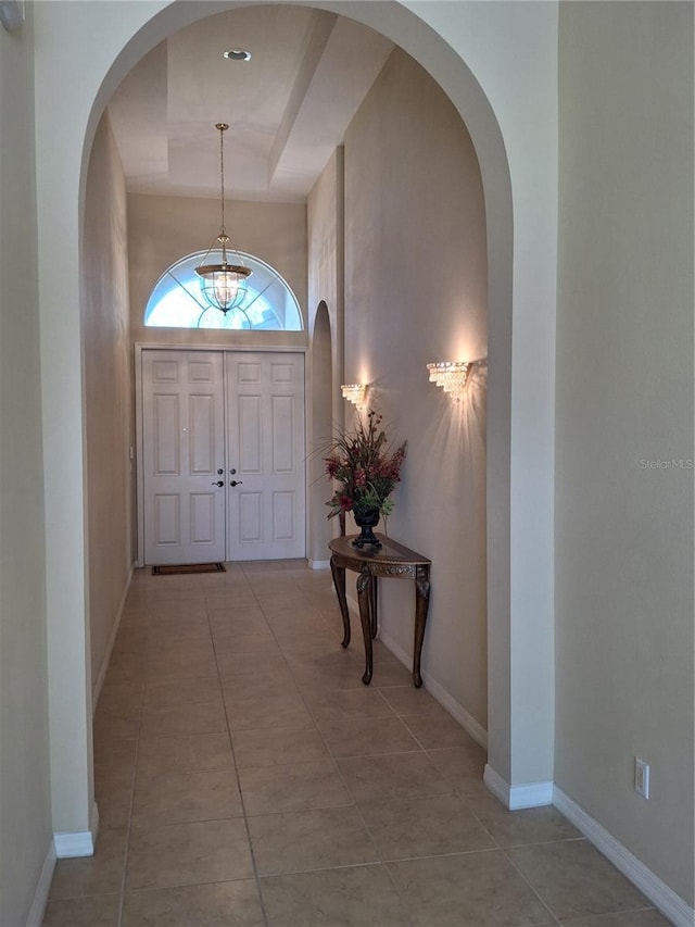 entryway featuring tile patterned flooring, baseboards, and a raised ceiling