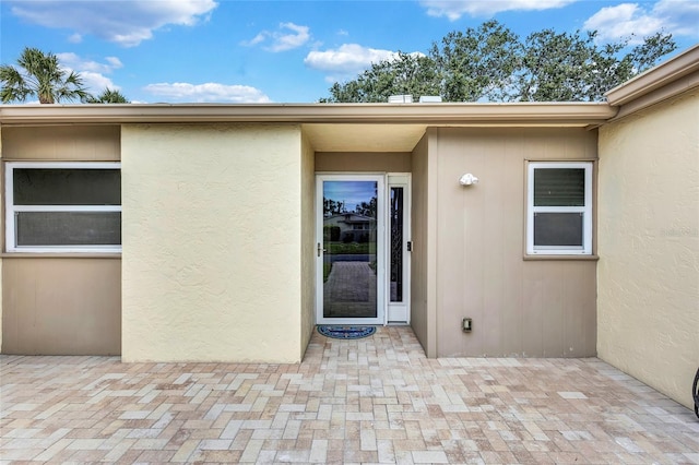 doorway to property with a patio and stucco siding