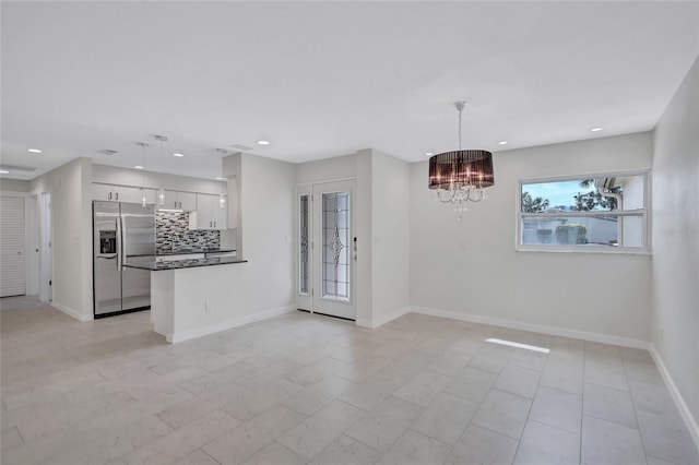 unfurnished dining area featuring recessed lighting, baseboards, and a chandelier