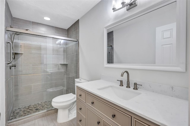 full bath featuring toilet, a stall shower, and vanity