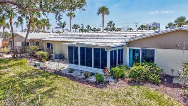 rear view of property with a lawn and a sunroom