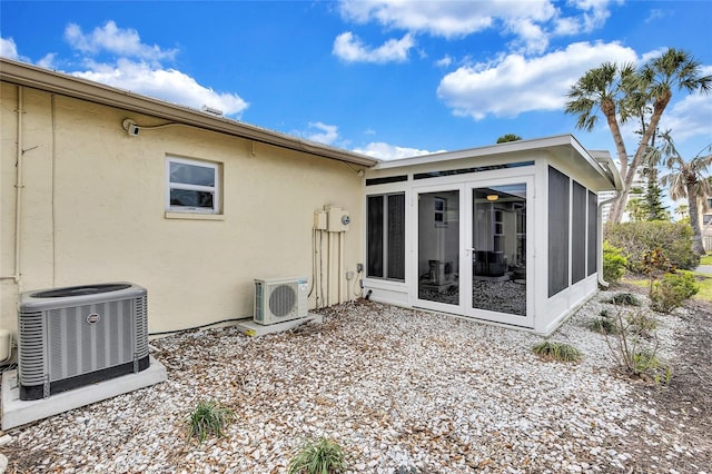 back of property with stucco siding, ac unit, cooling unit, and a sunroom