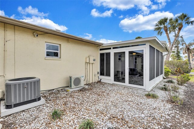 back of property with stucco siding, ac unit, cooling unit, and a sunroom